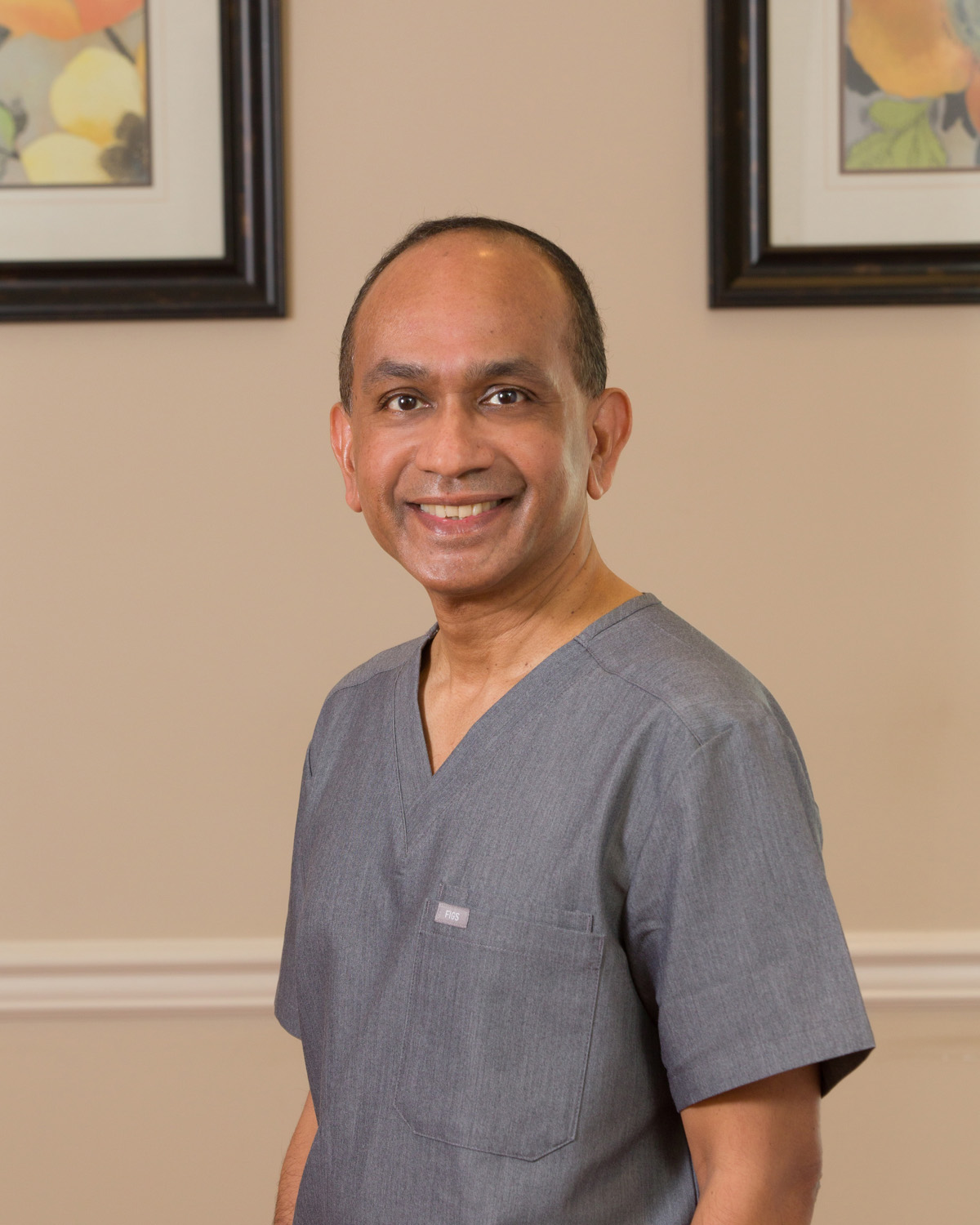Dr. Vel Natesan posing in medical scrubs
